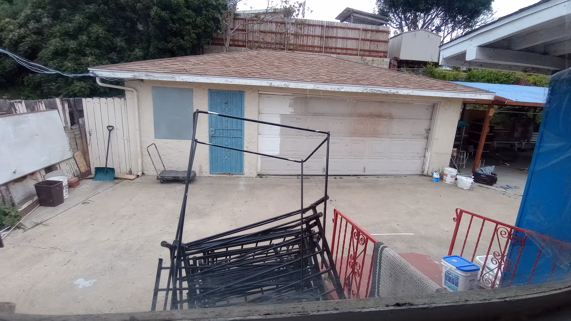 Exterior view of a small building with a blue door and a cluttered driveway.
