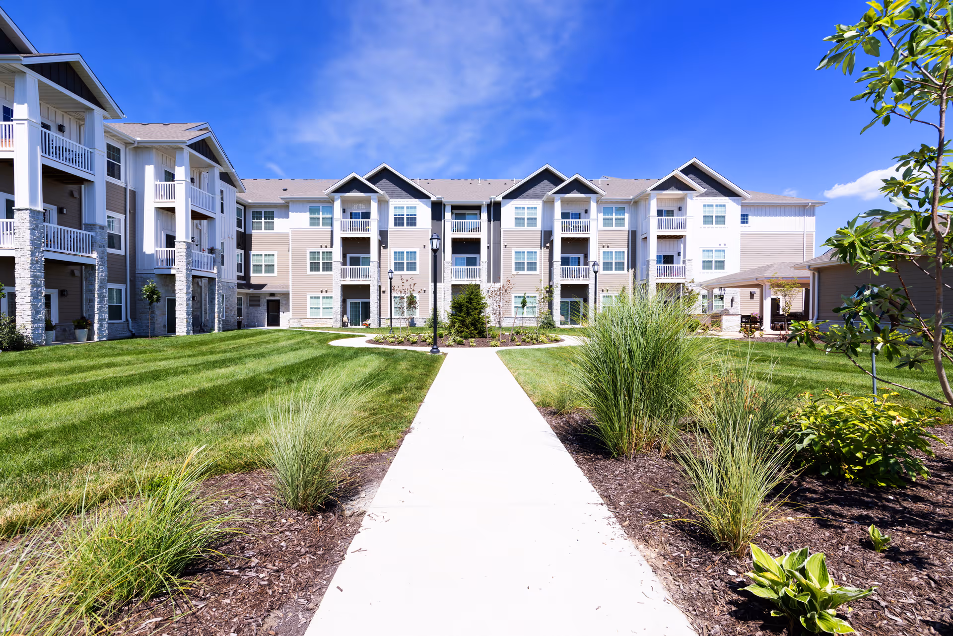 Pathway leads to a multi-building senior living campus with landscaped grounds.