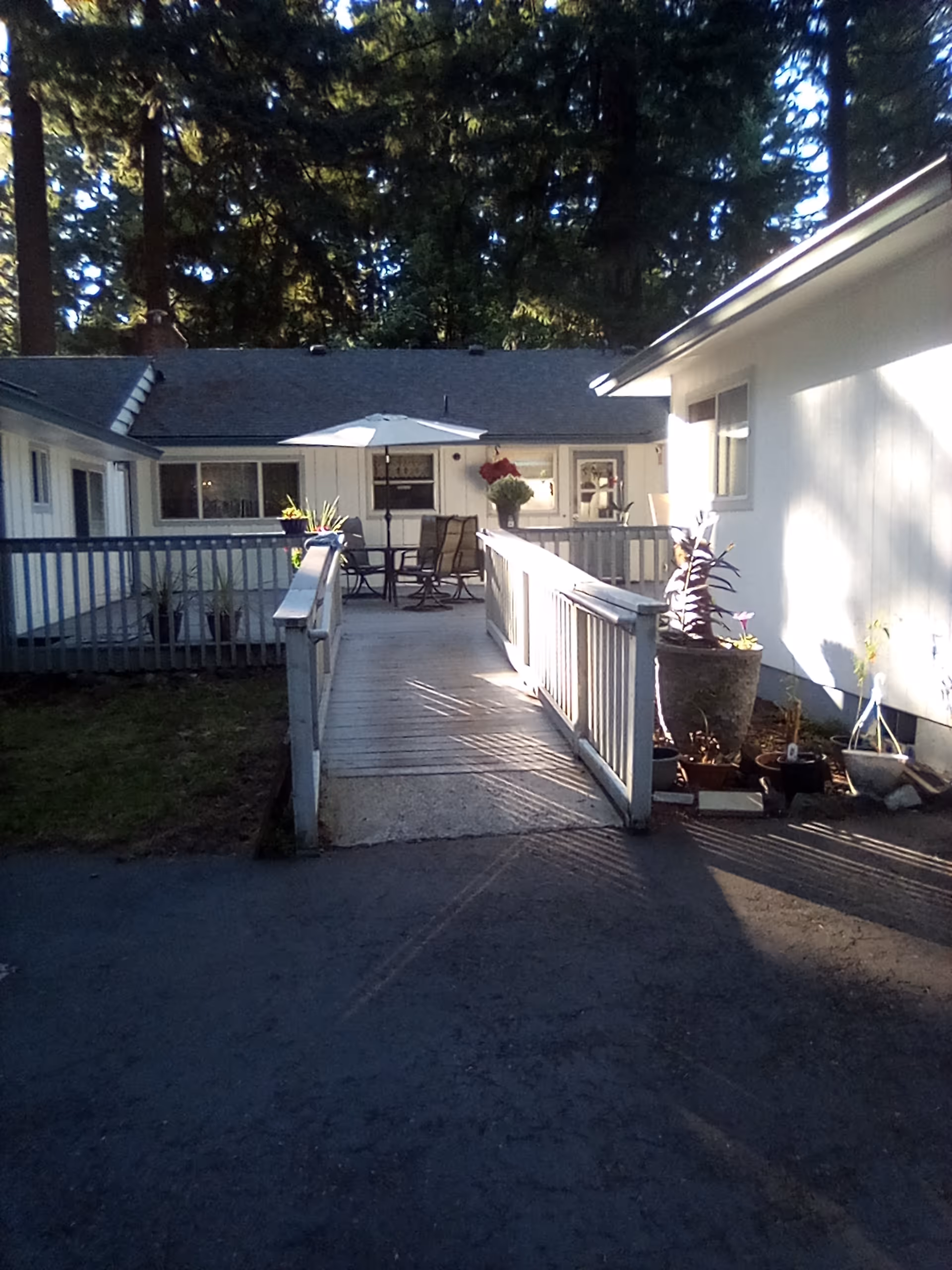 Outdoor courtyard with patio seating, umbrella, and potted plants at Amor Family Home.