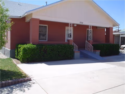 Red brick adult care home with hedges and two front entrances.