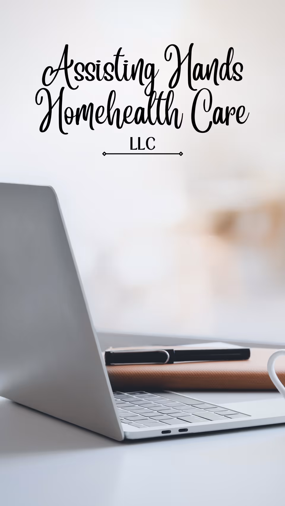 Laptop on a desk with blurred background and wall sign reading Assisting Hands Homehealth Care LLC