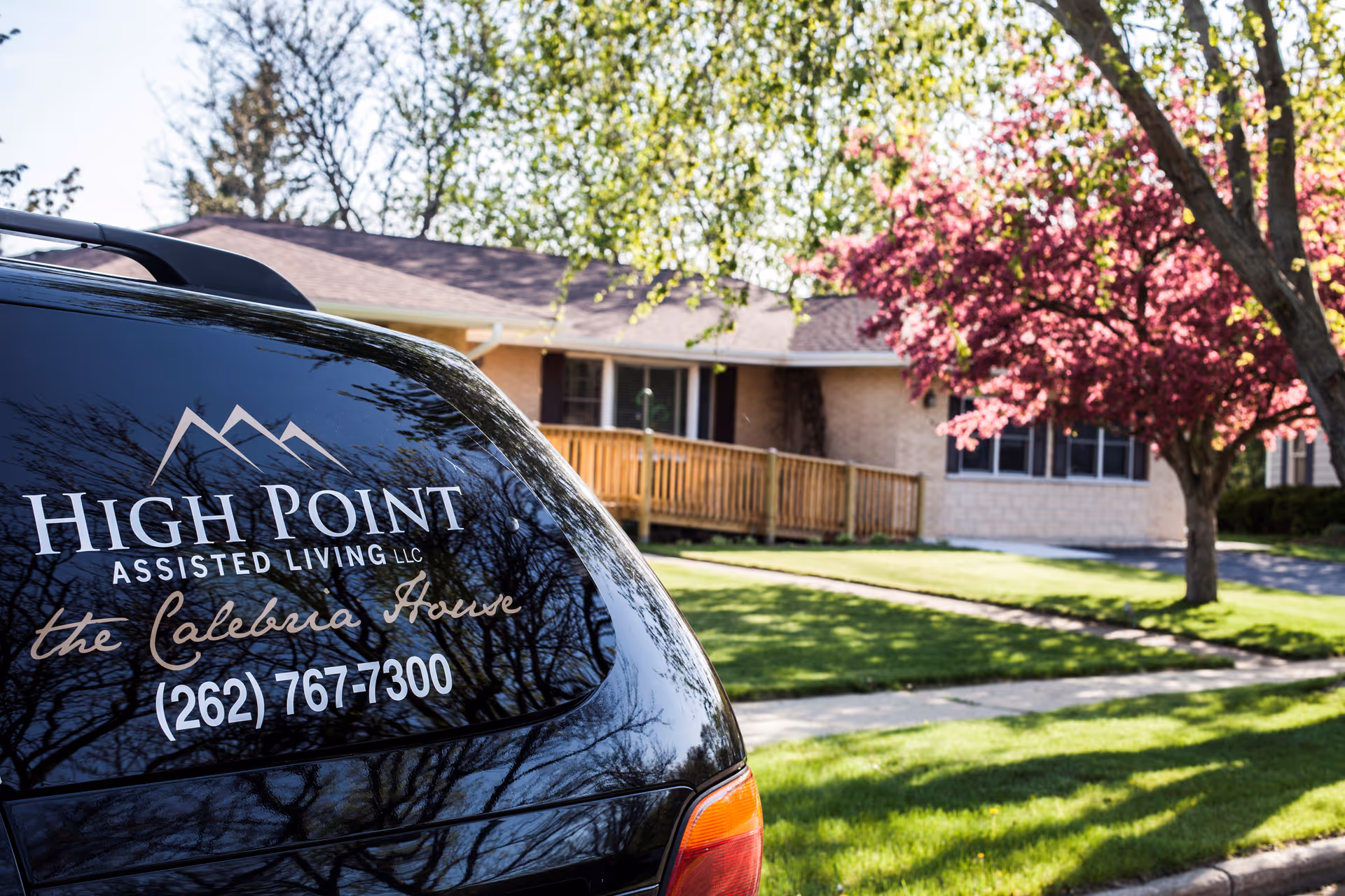 Exterior view of Calebria House assisted living with a branded vehicle parked outside.