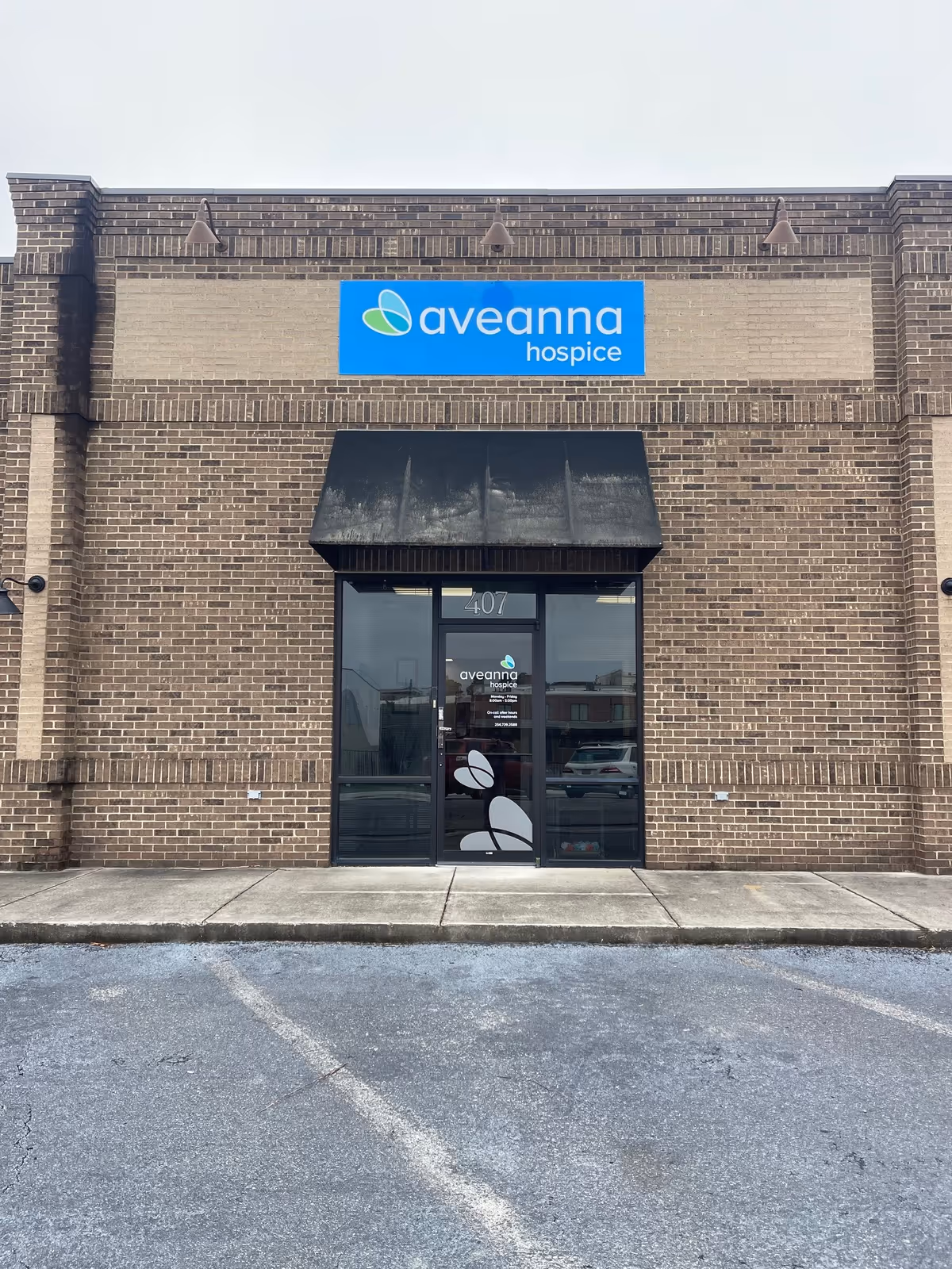 Brick exterior Aveanna Hospice building with blue sign above glass entrance