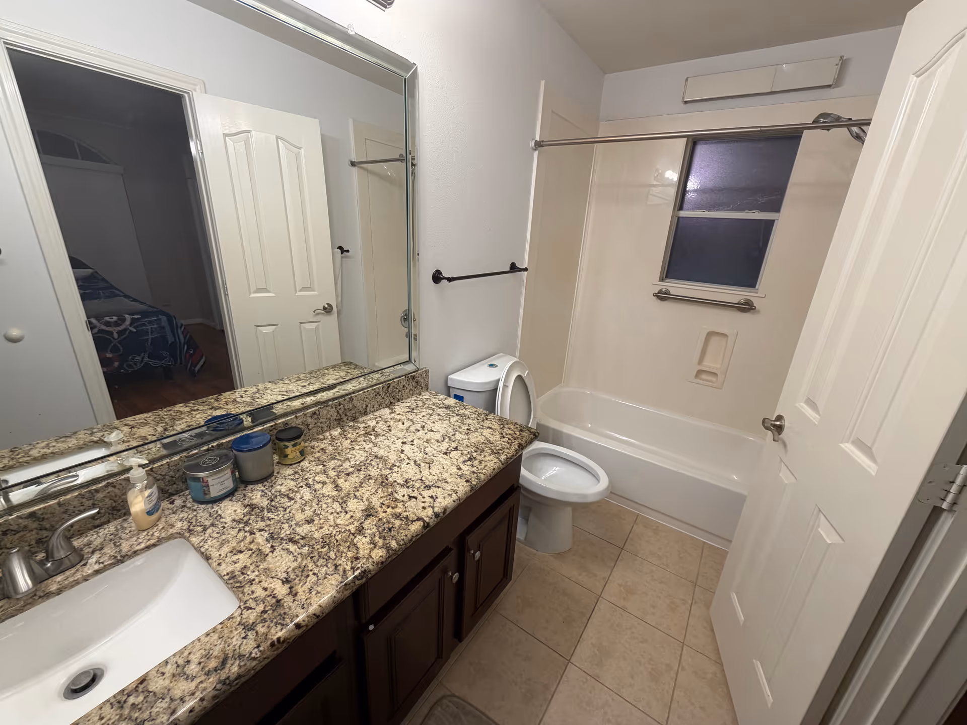 This bathroom features a granite vanity, sink, toilet, and a bathtub/shower.
