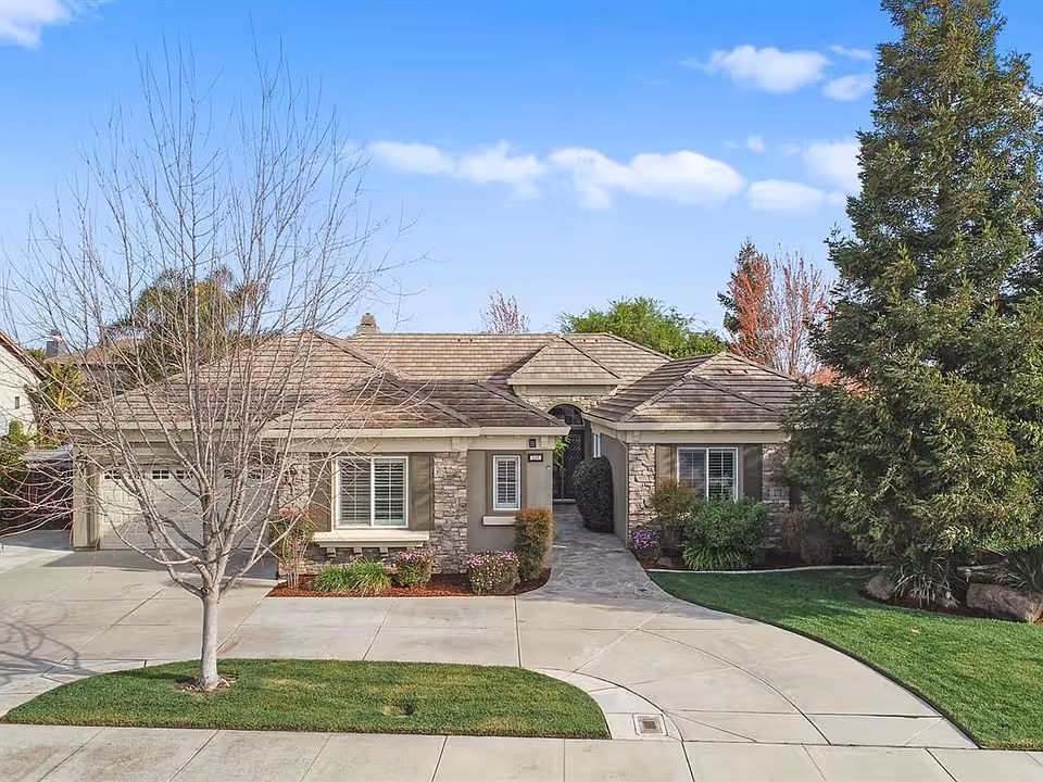 Single-story building with stone accents and a curved walkway to the entrance, landscaped.
