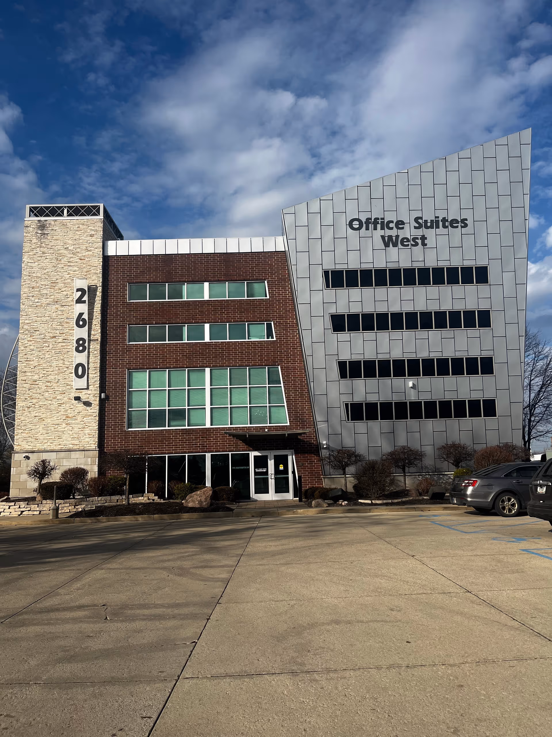 Exterior view of a modern building with brick and metal panels and a parking lot