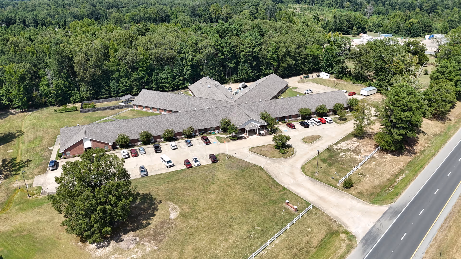 Aerial view of a single-story senior living facility with a parking lot and surrounding trees.
