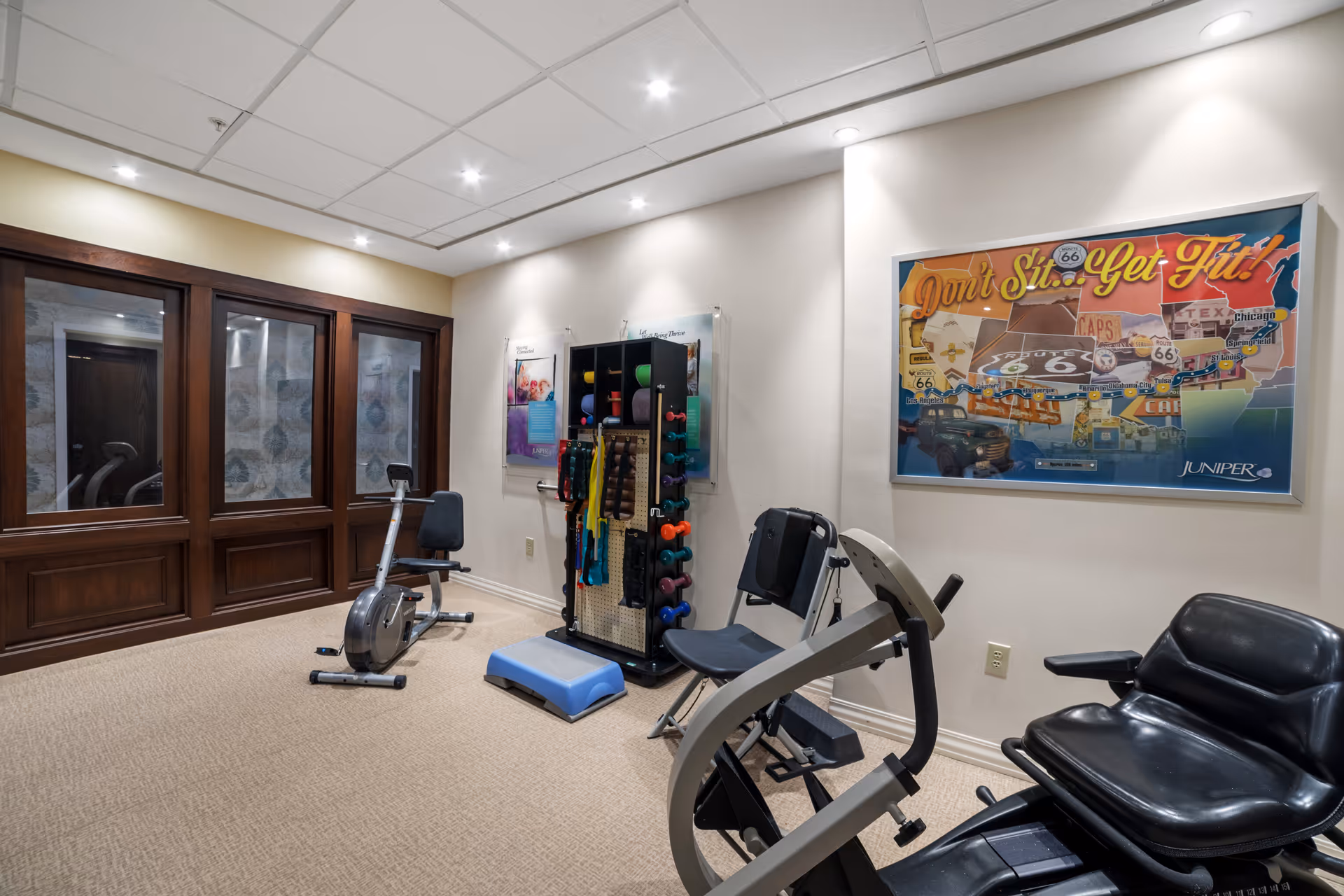 A small indoor fitness room with exercise machines and weights.