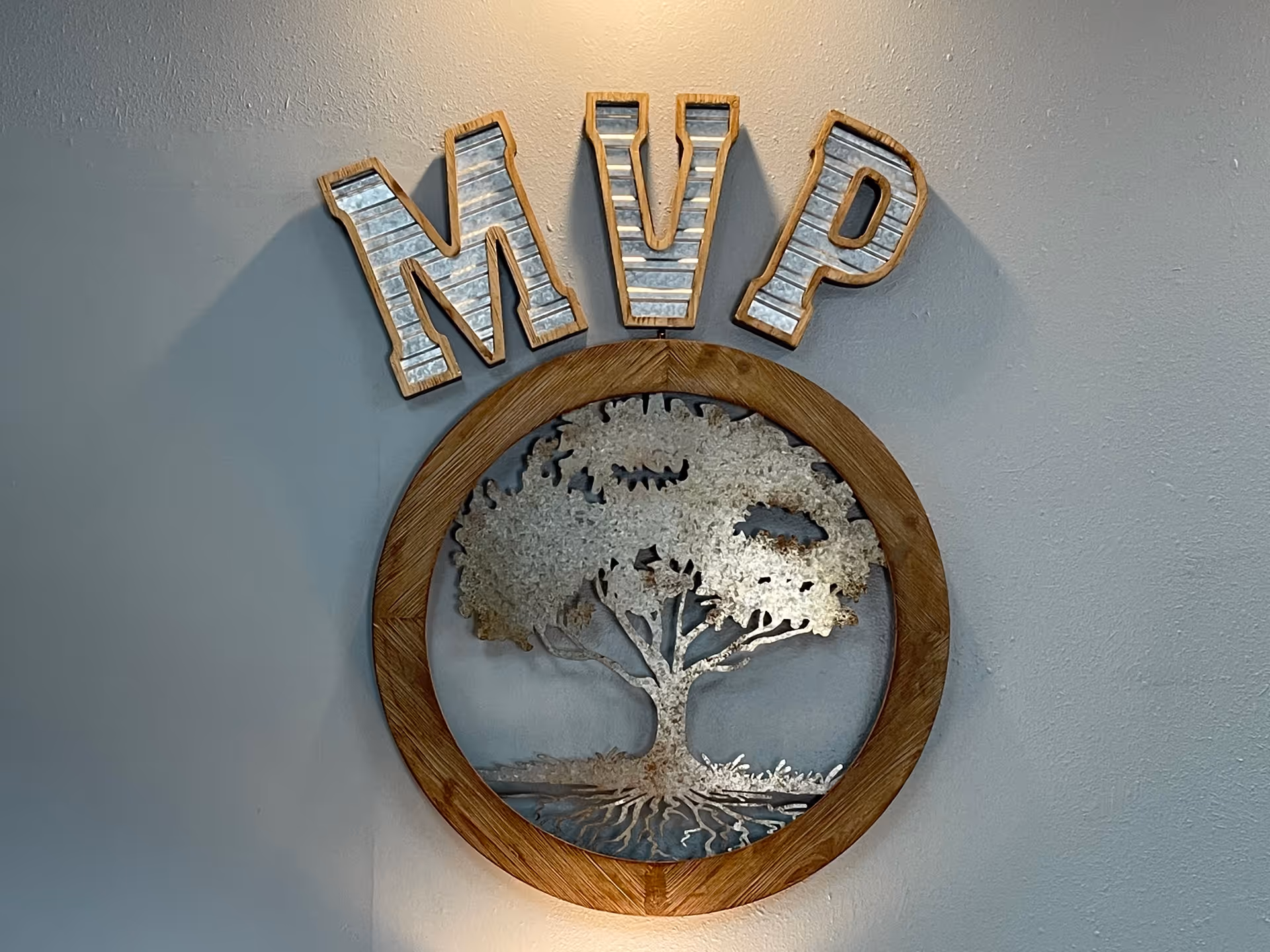 MVP letters above circular metal tree wall sculpture on blue interior wall
