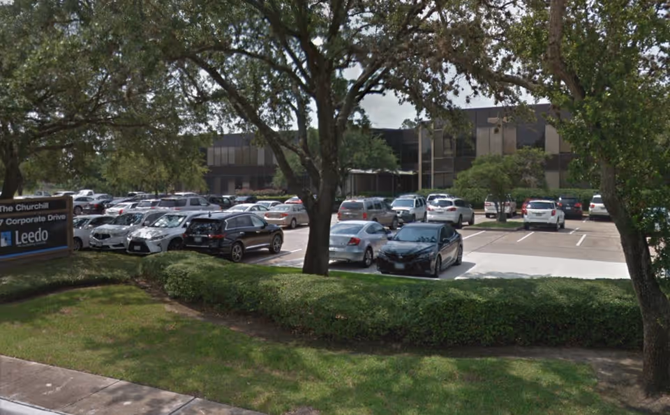 Exterior view of a parking lot with trees and a modern building.