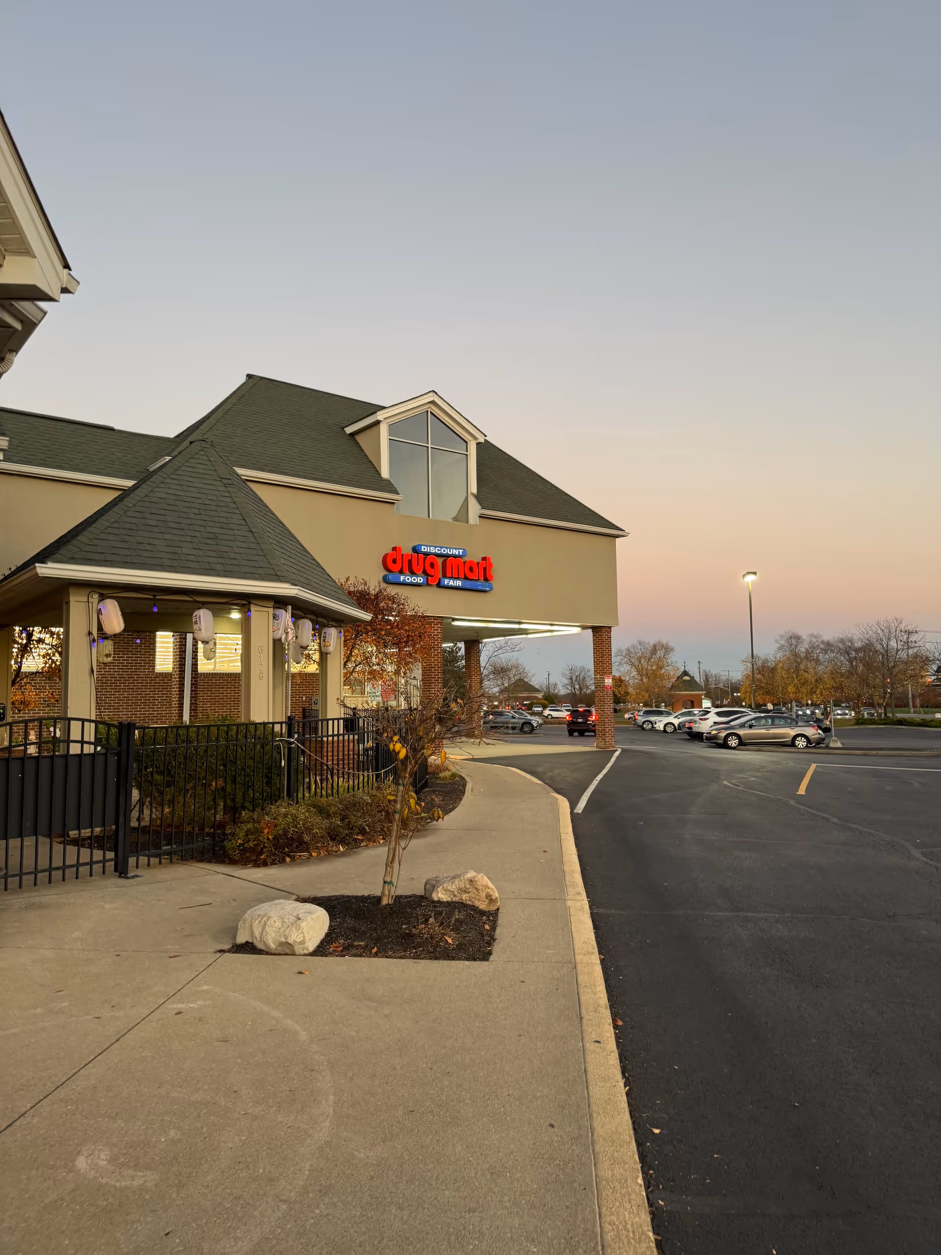 Exterior view of Discount Drug Mart storefront with parking lot and walkway.