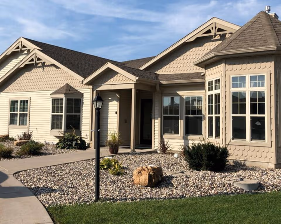 Front view of a beige senior living facility with rock landscaping