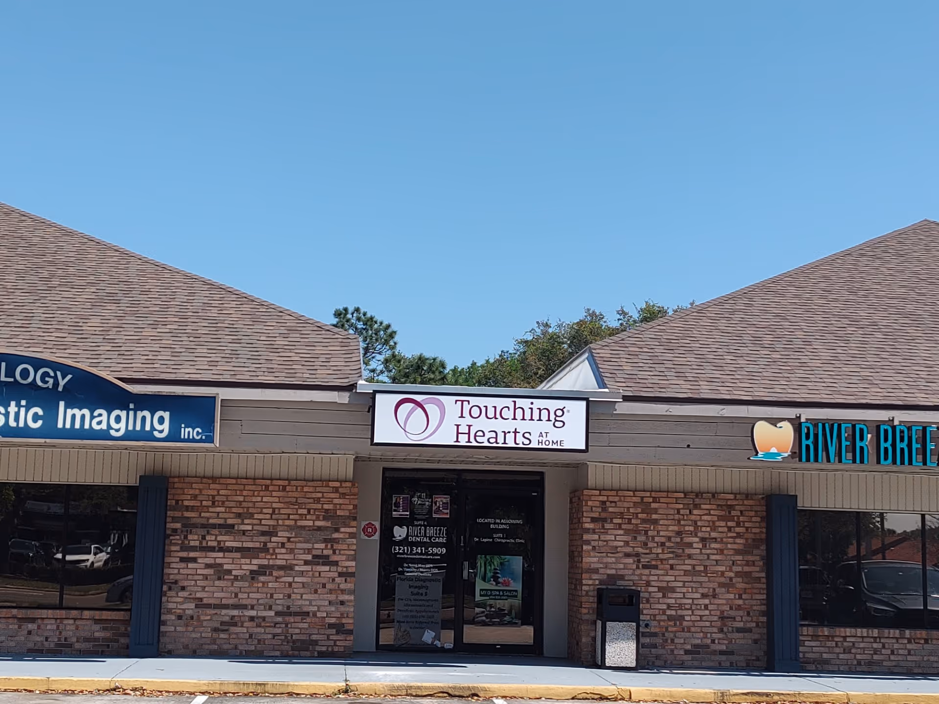 Exterior storefront with Touching Hearts at Home sign between neighboring businesses