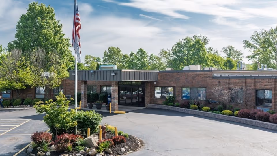 Exterior view of Legacy Barberton with brick facade, entrance, flagpole, and landscaped parking.
