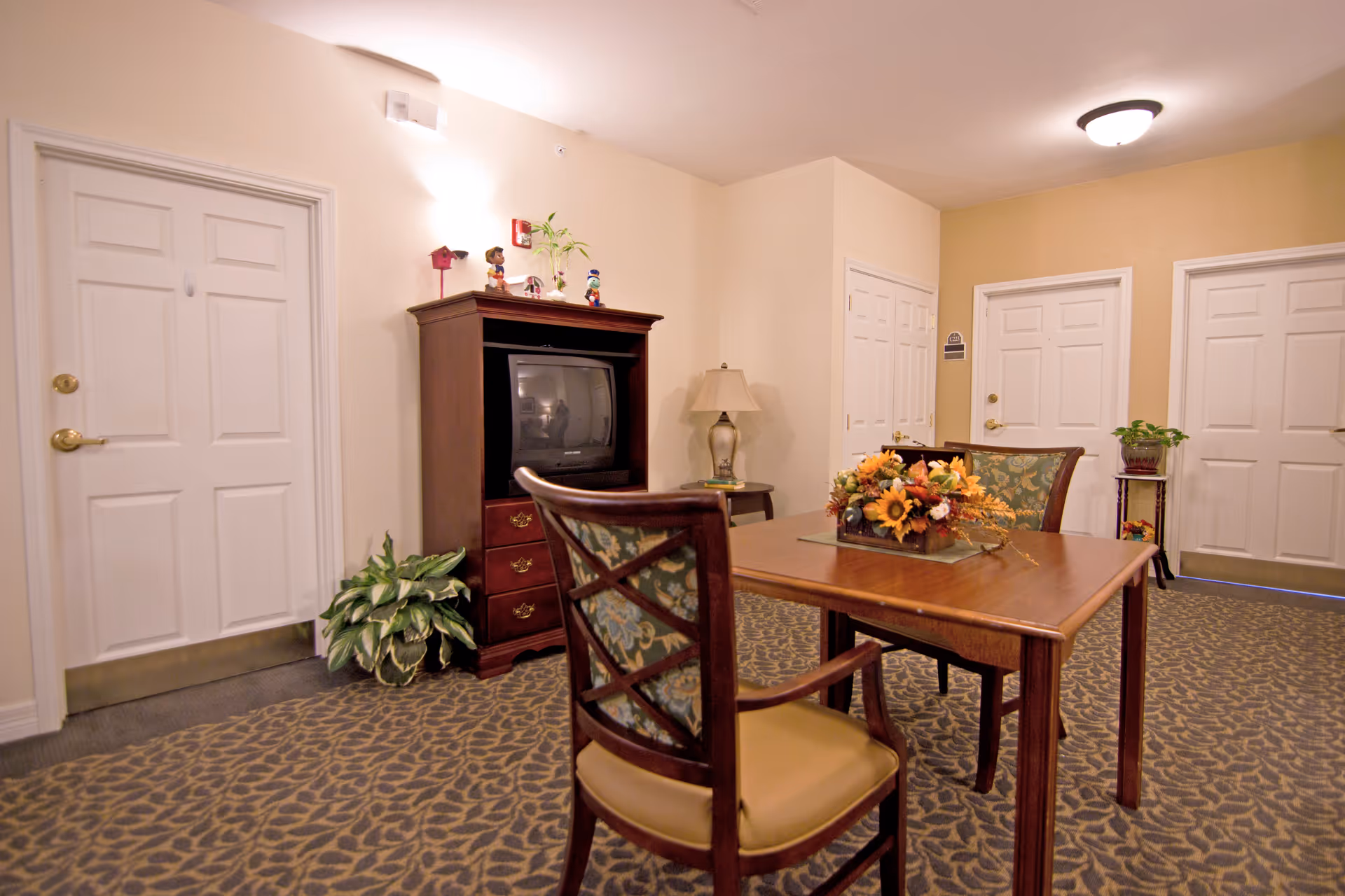 A cozy dining room in a senior living facility with a wooden table and chairs.