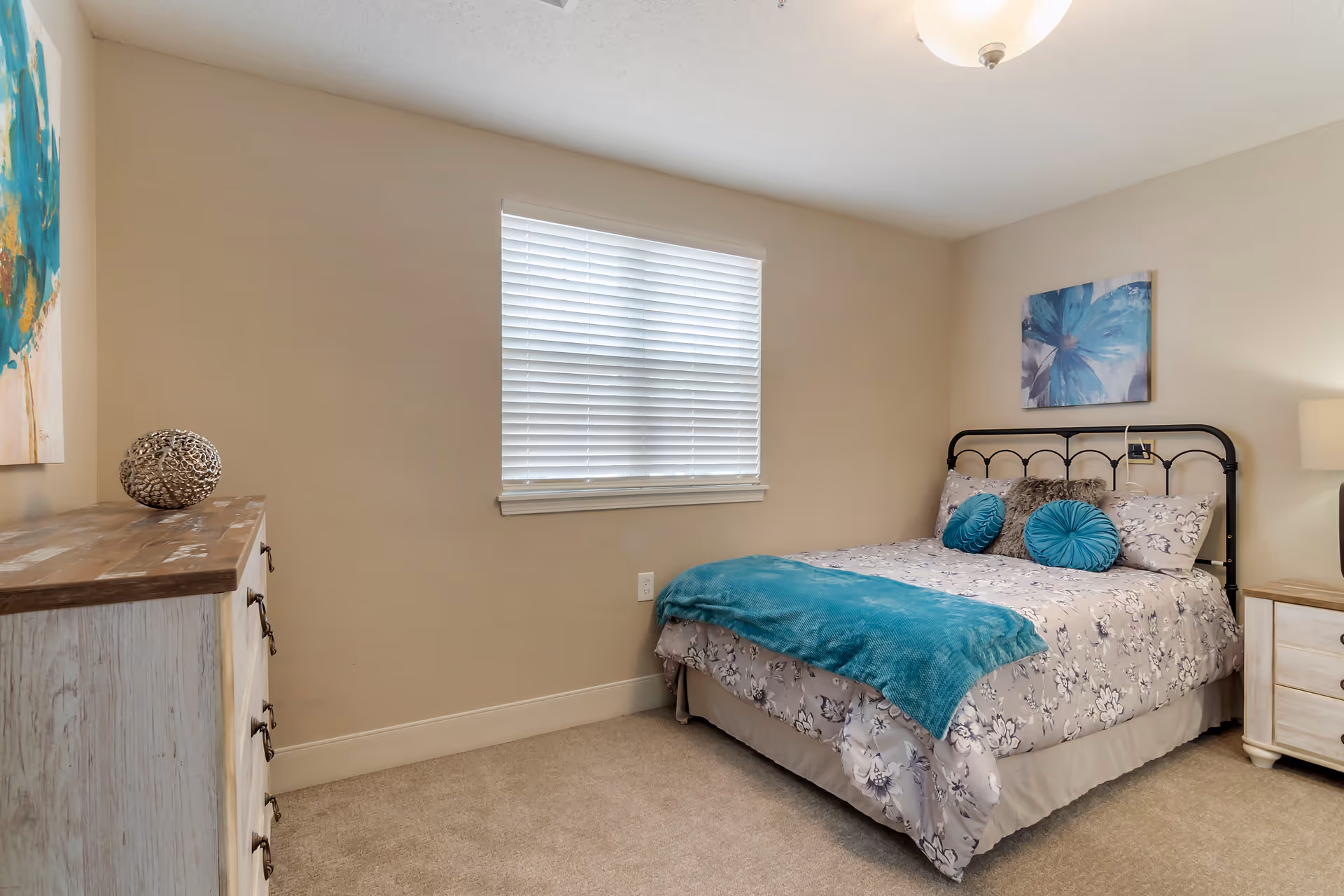 Bedroom with a metal bed, teal accents, dresser, and window blinds.