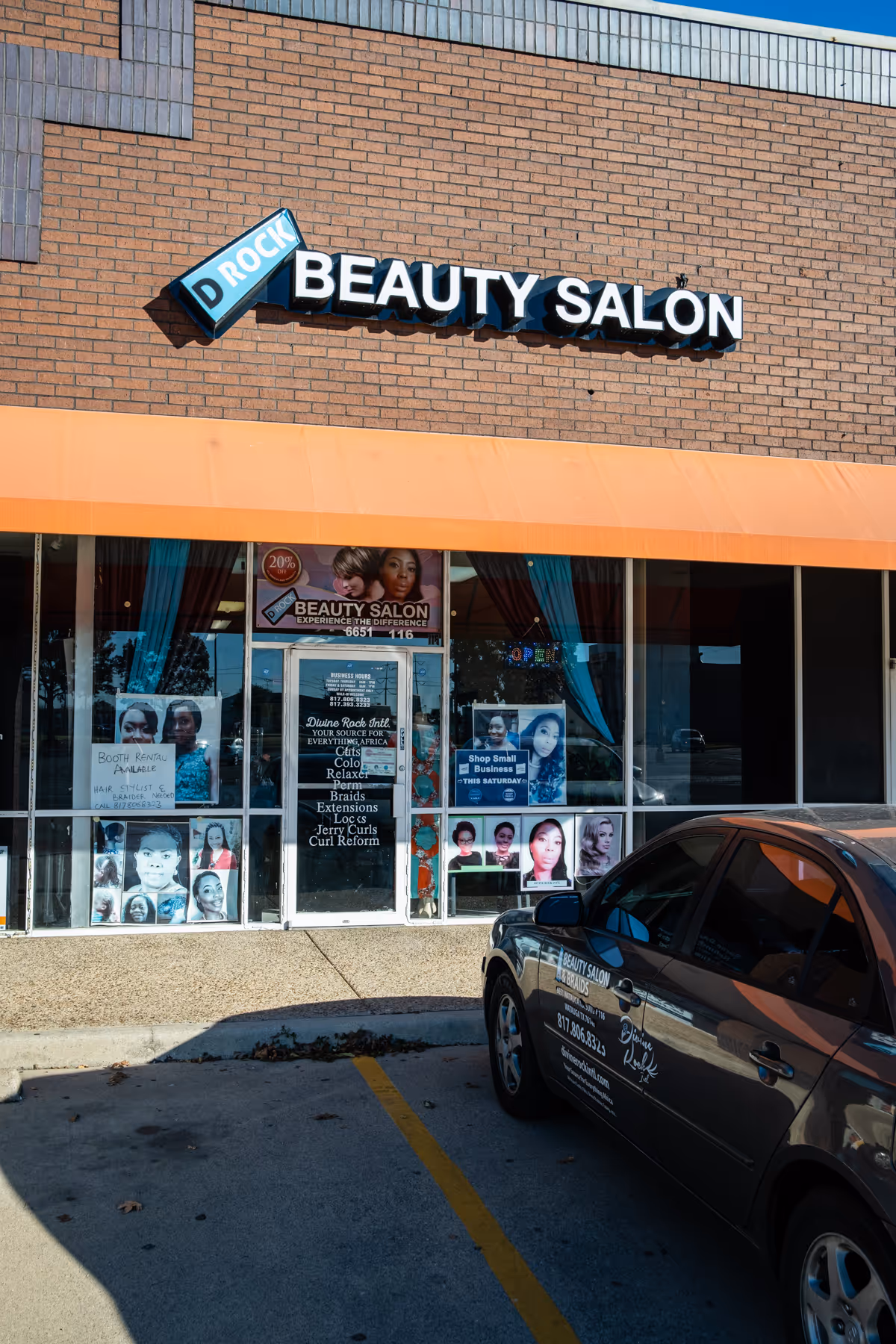 Brick storefront with D Rock Beauty Salon sign and posters in the windows