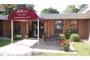 Exterior view of an assisted living entrance with maroon canopy and flowers