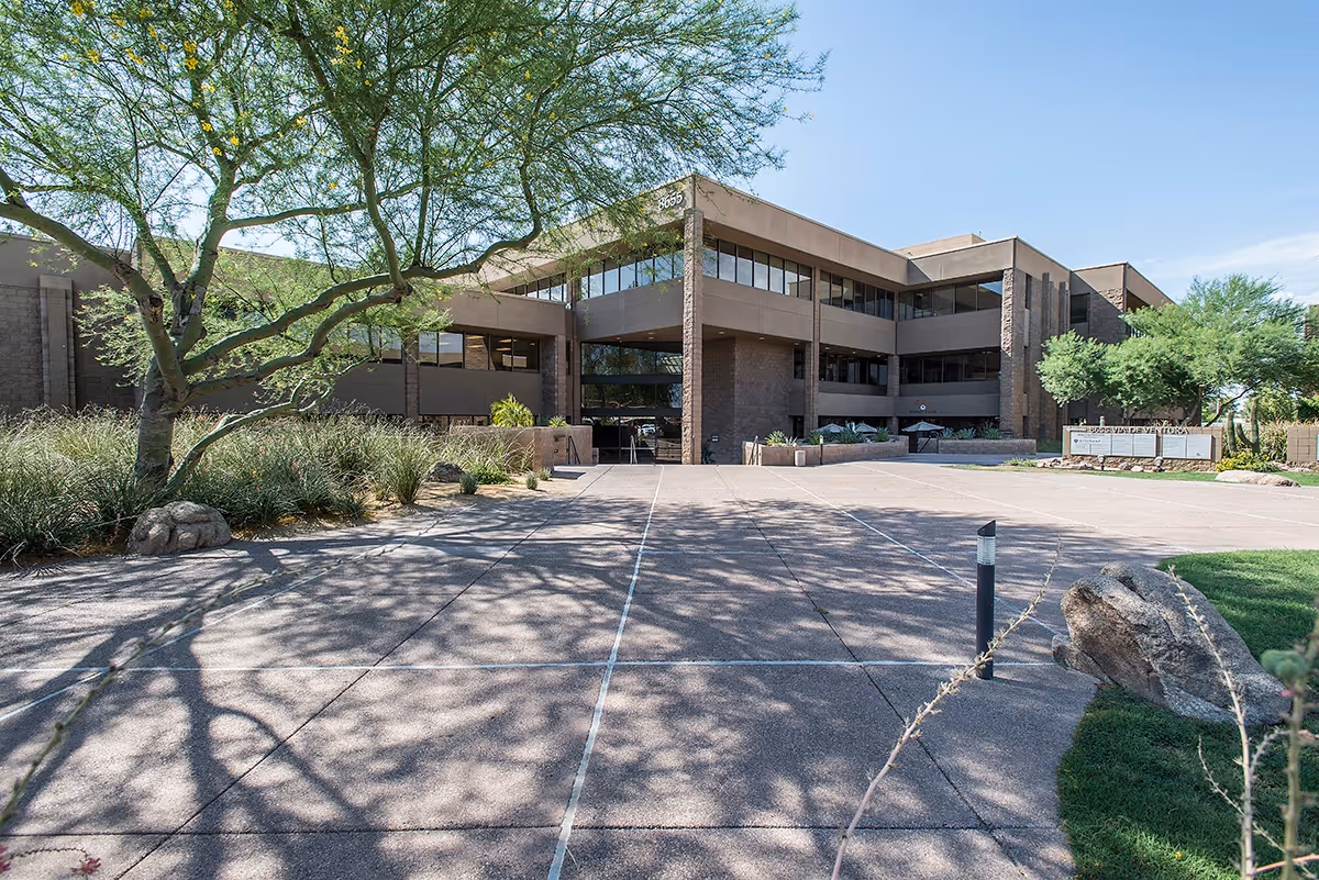Wide paved entrance of a modern senior living facility with trees and landscaping