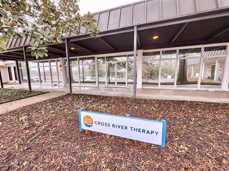Exterior view of a therapy facility with glass doors and a Cross River Therapy sign.