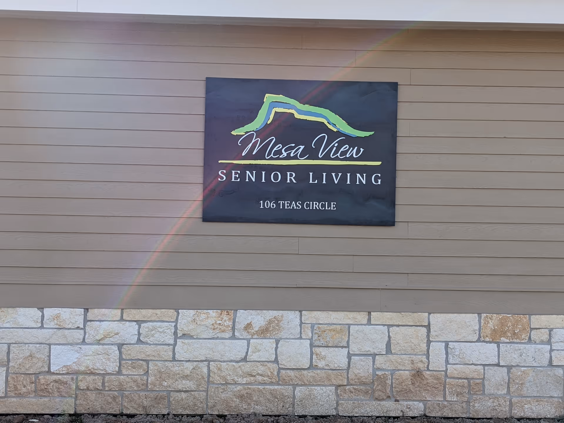 Exterior wall with Mesa View Senior Living sign mounted above a stone base