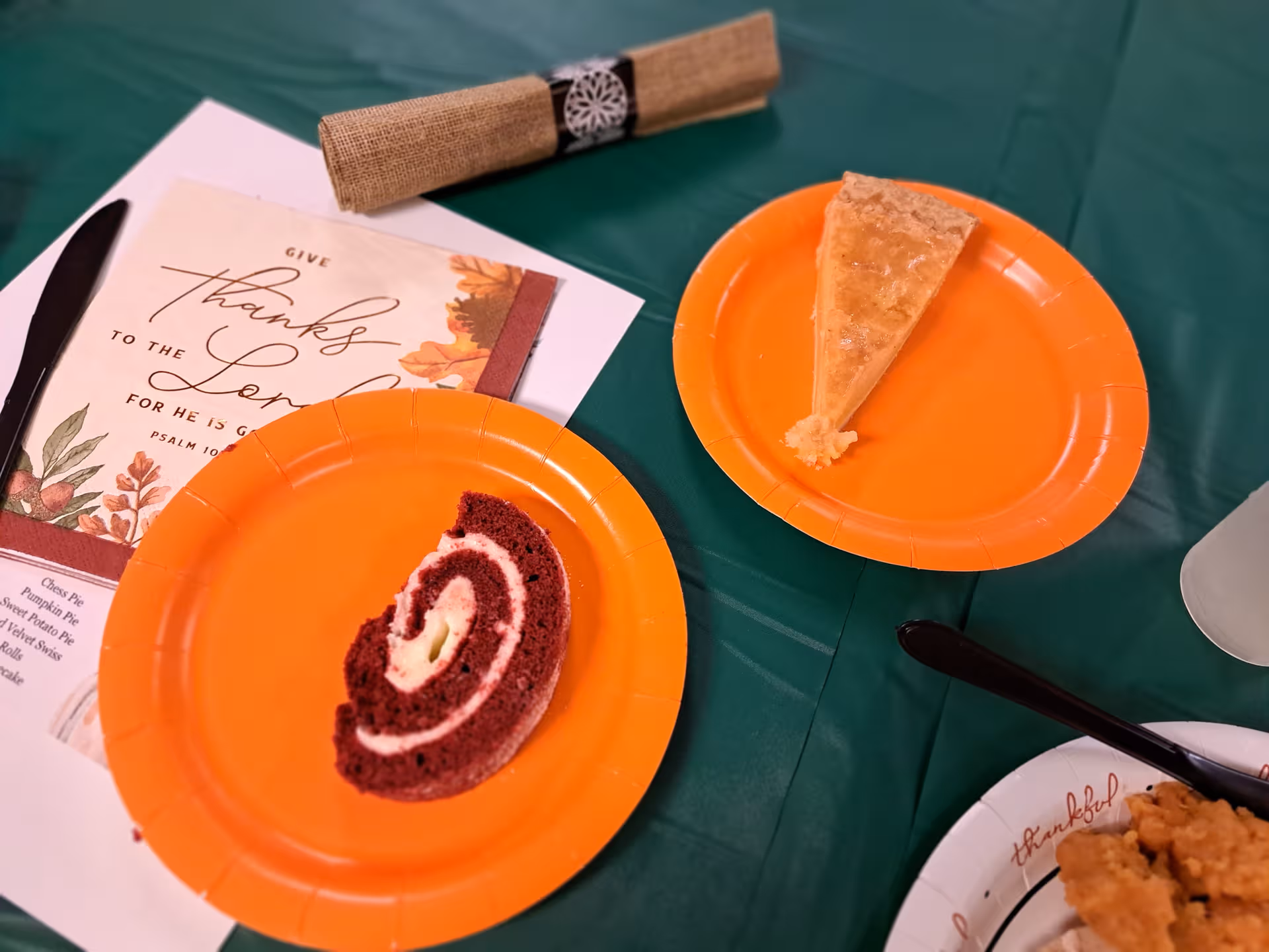 Orange plates with cake slices and a Thanksgiving card on a table.