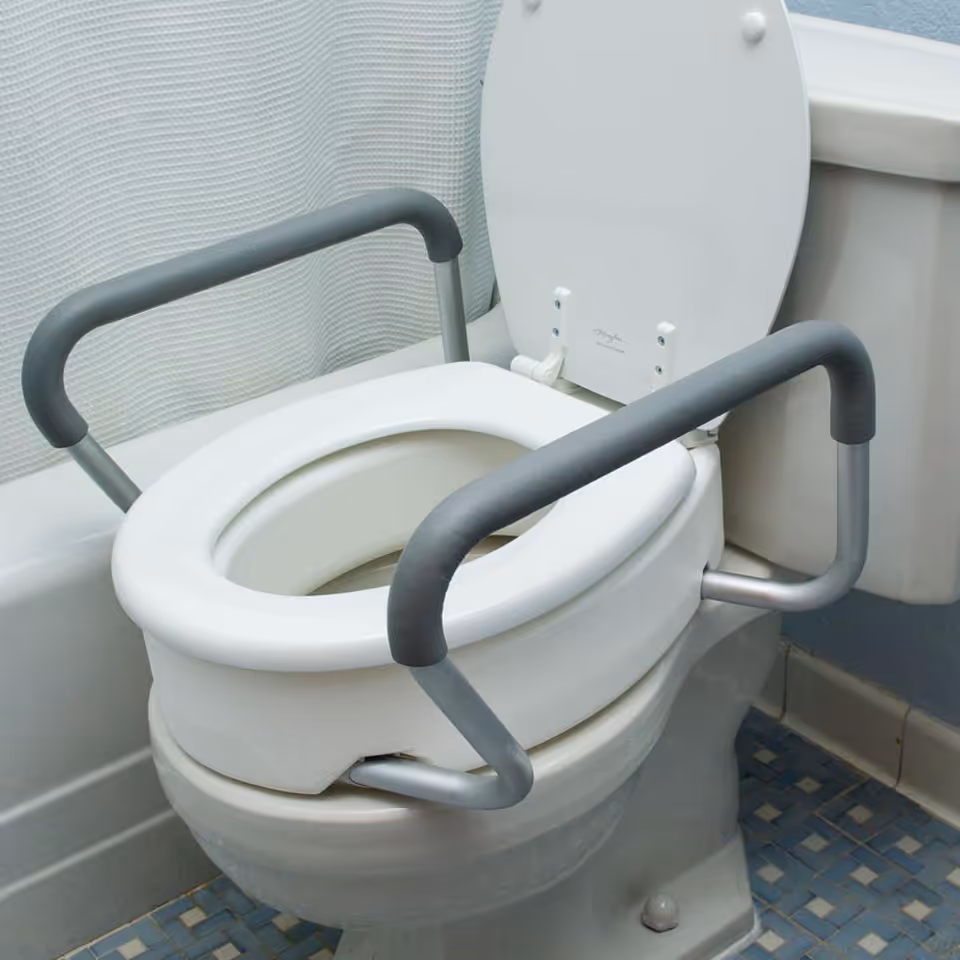 Accessible restroom toilet with safety rails in a pale-blue tiled bathroom.