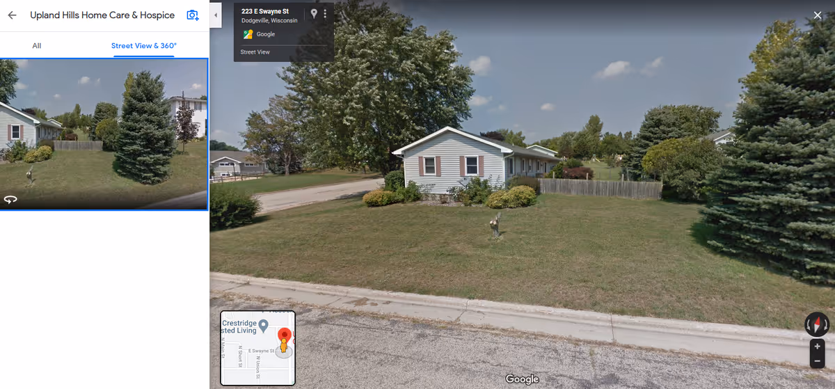 Front yard and single-story house along a quiet suburban street with trees.