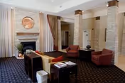 Lounge area with seating, fireplace, and stone columns in a senior living lobby.