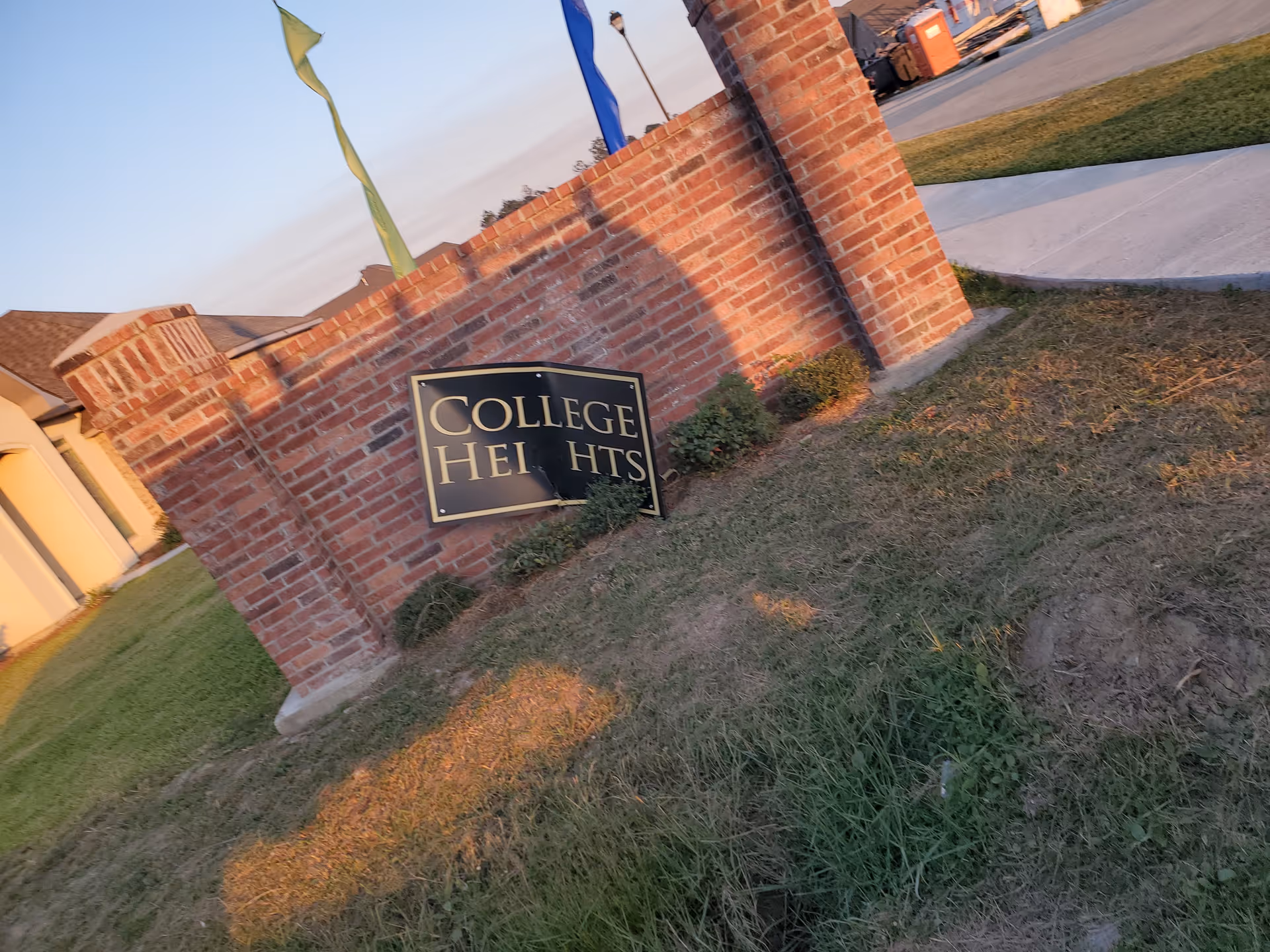 Brick entrance with a College Heights sign beside a grassy lawn