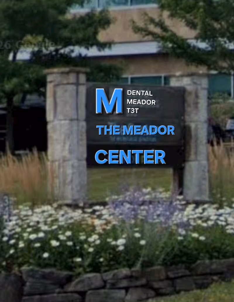 Front exterior sign with stone pillars and flowers reading The Meador Center