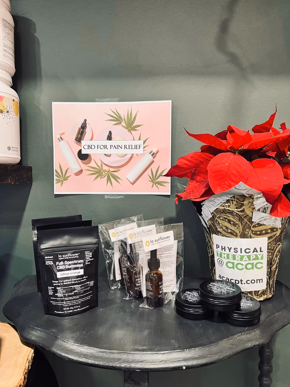 CBD product display on round table beside red poinsettia in a clinical interior.