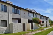 Two-story light-gray brick senior living building with windows and landscaped walkway.