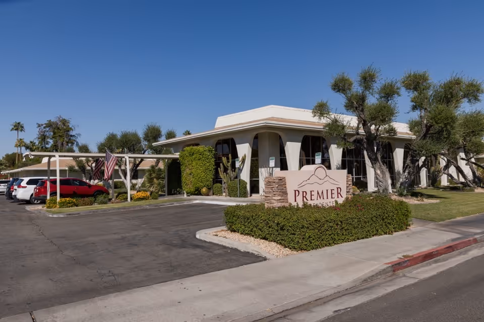 Exterior view of Premier Care Center for Palm Springs with a sign and parked cars.