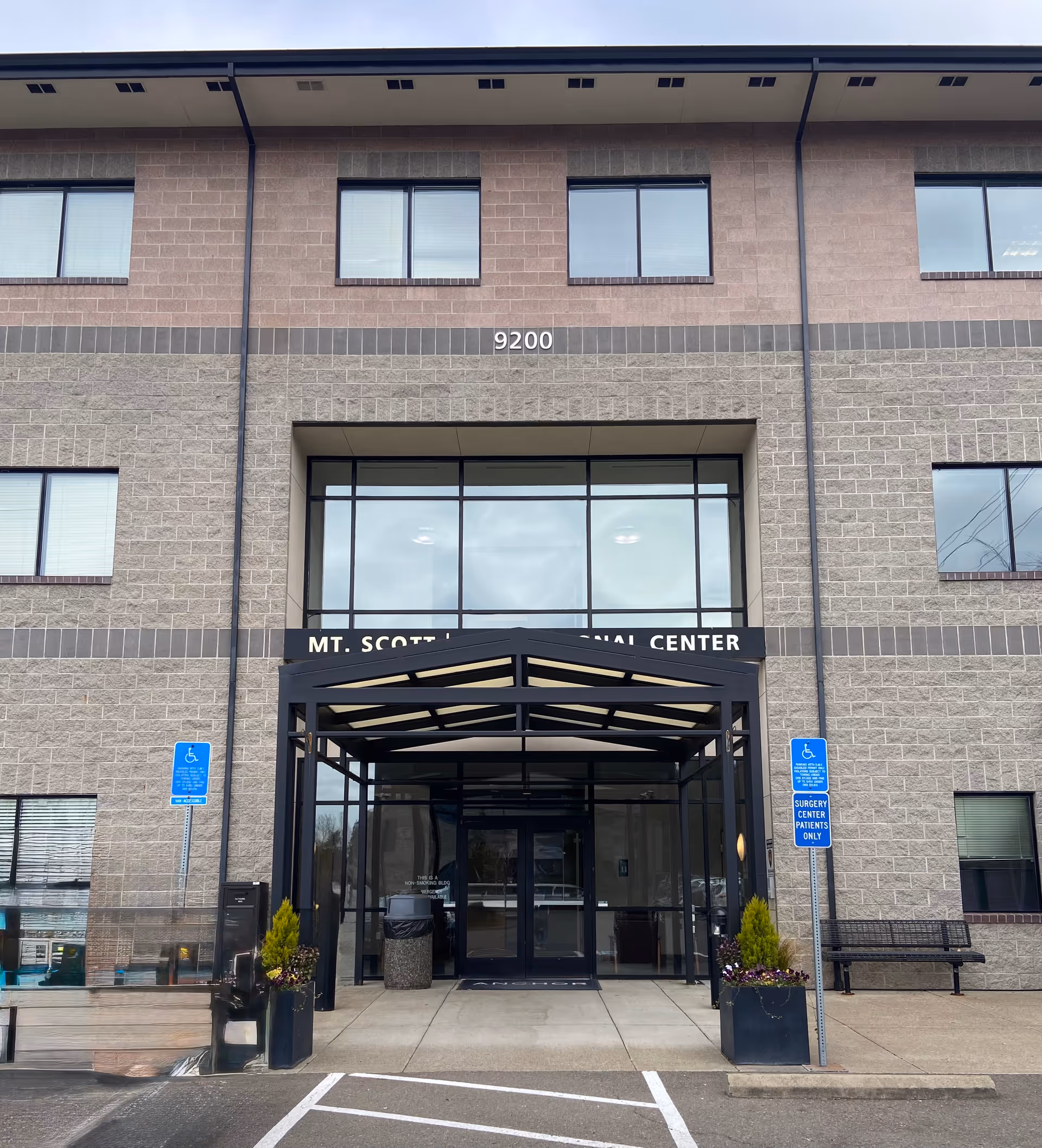 Front view of a brick building with glass entryway and handicap parking signs.