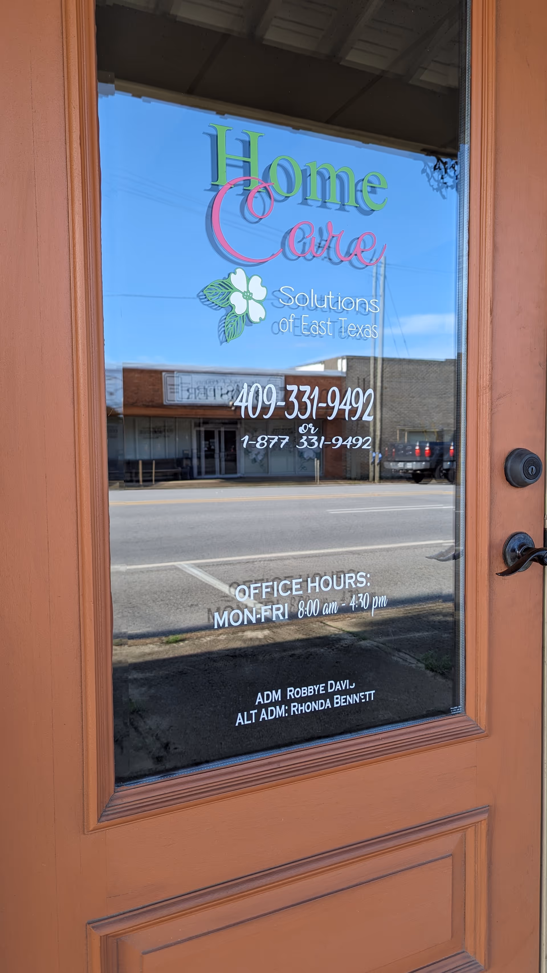 Glass front door displaying Home Care Solutions signage and street reflection.