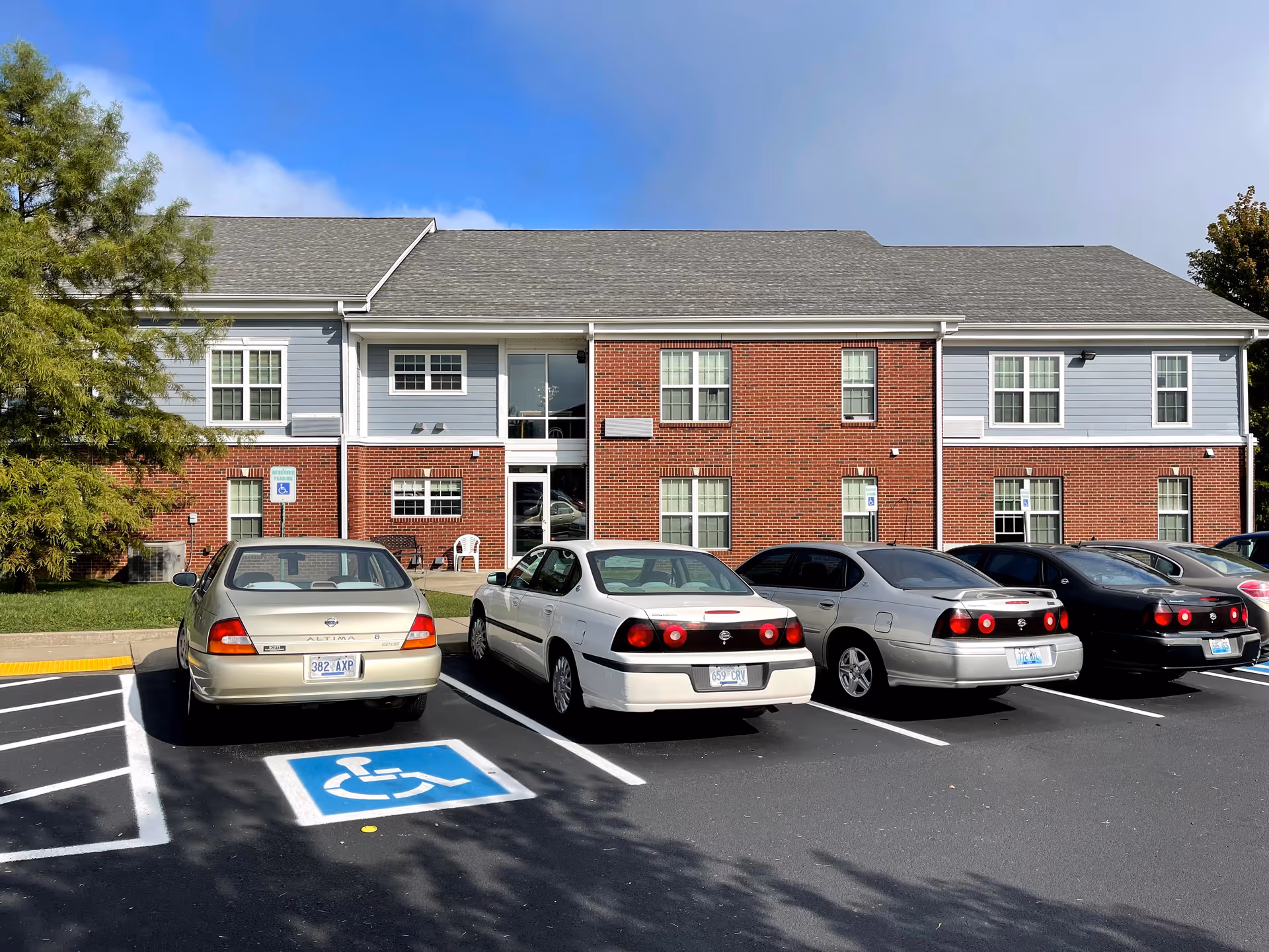 Two-story brick senior housing building with a parking lot in front.