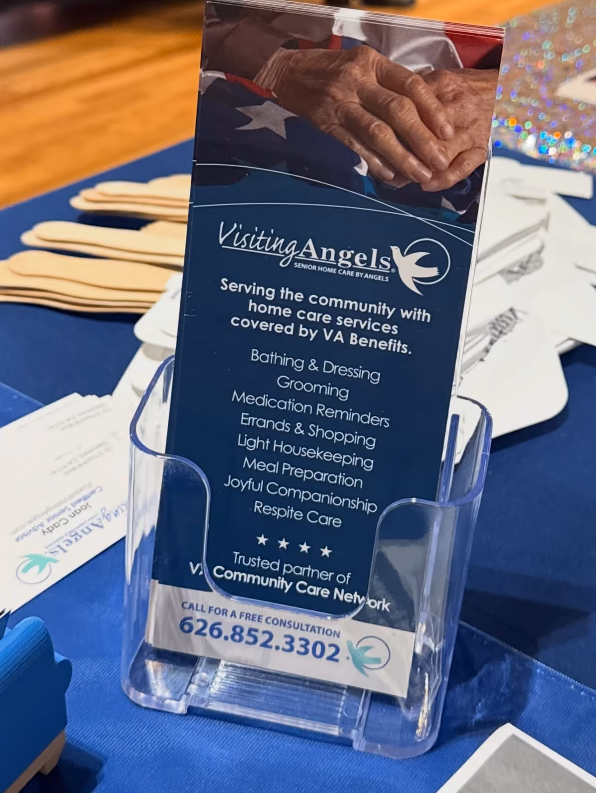 Blue Visiting Angels brochure in a clear acrylic stand on a blue tablecloth.