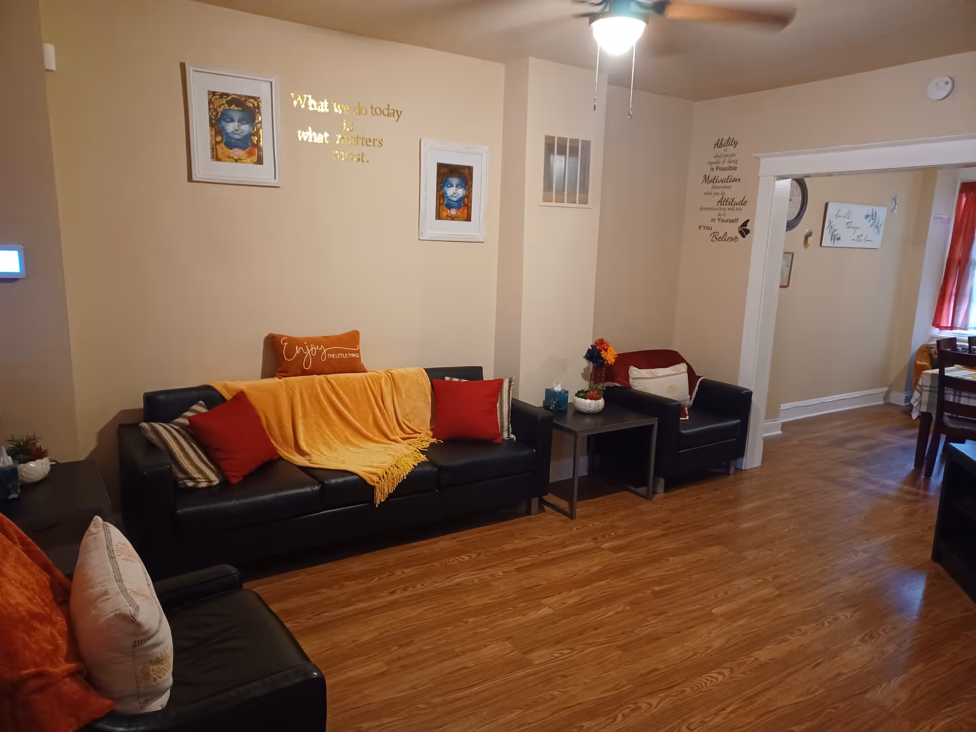 Cozy common living room with black sofas, warm blankets, and wall decor.