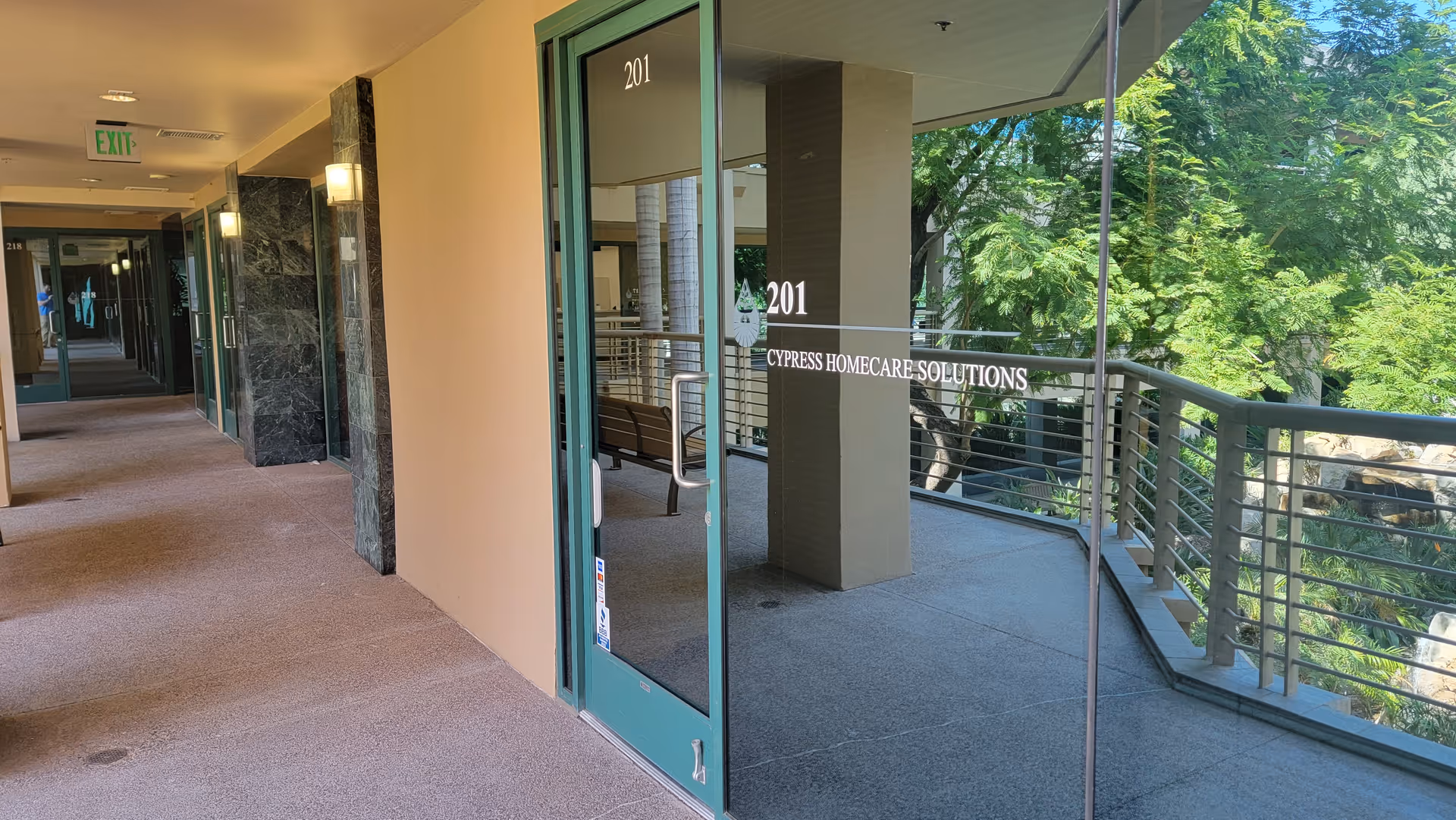 Glass entrance door for Cypress HomeCare Solutions opens to a hallway and outdoor balcony.