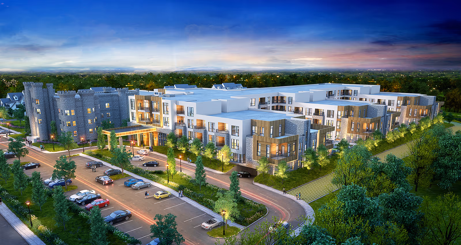 Aerial view of The 501 at Mattison Estate, a large senior living facility with modern architecture and a castle-like stone building on one side. The facility is surrounded by trees and greenery, with a parking lot and cars in front. The sky is at dusk with a colorful horizon.