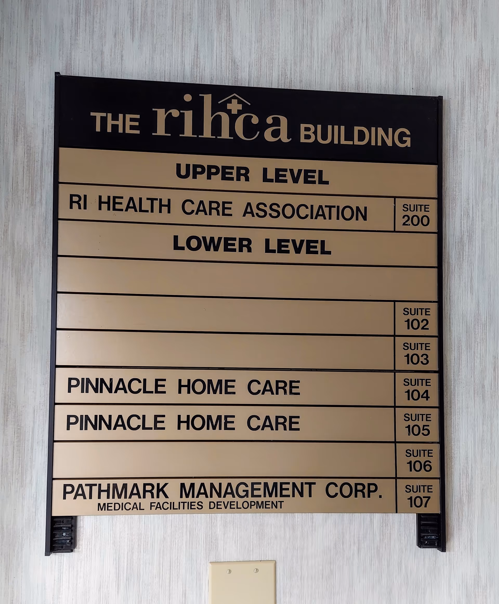 Interior wall signboard listing building names and suite numbers for Pinnacle Home Care