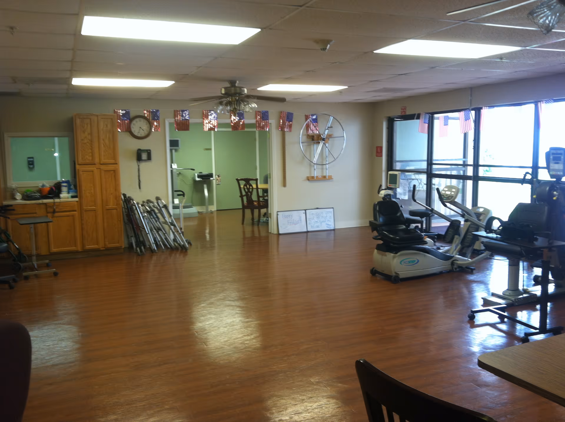 Spacious indoor rehabilitation gym with exercise bikes, cardio equipment, and wooden flooring.