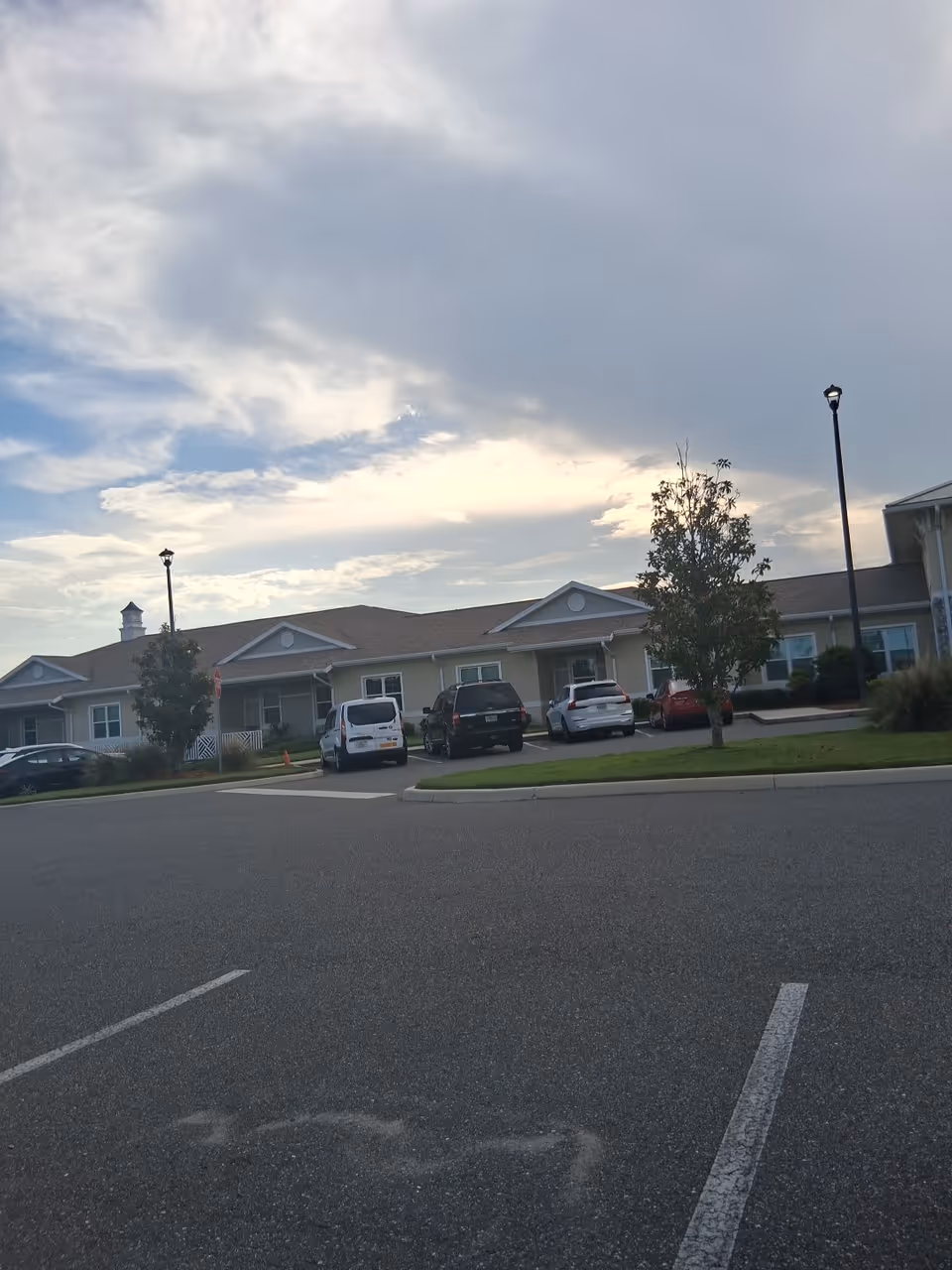 Front view of Apopka Health and Rehabilitation Center with parked cars and cloudy sky.