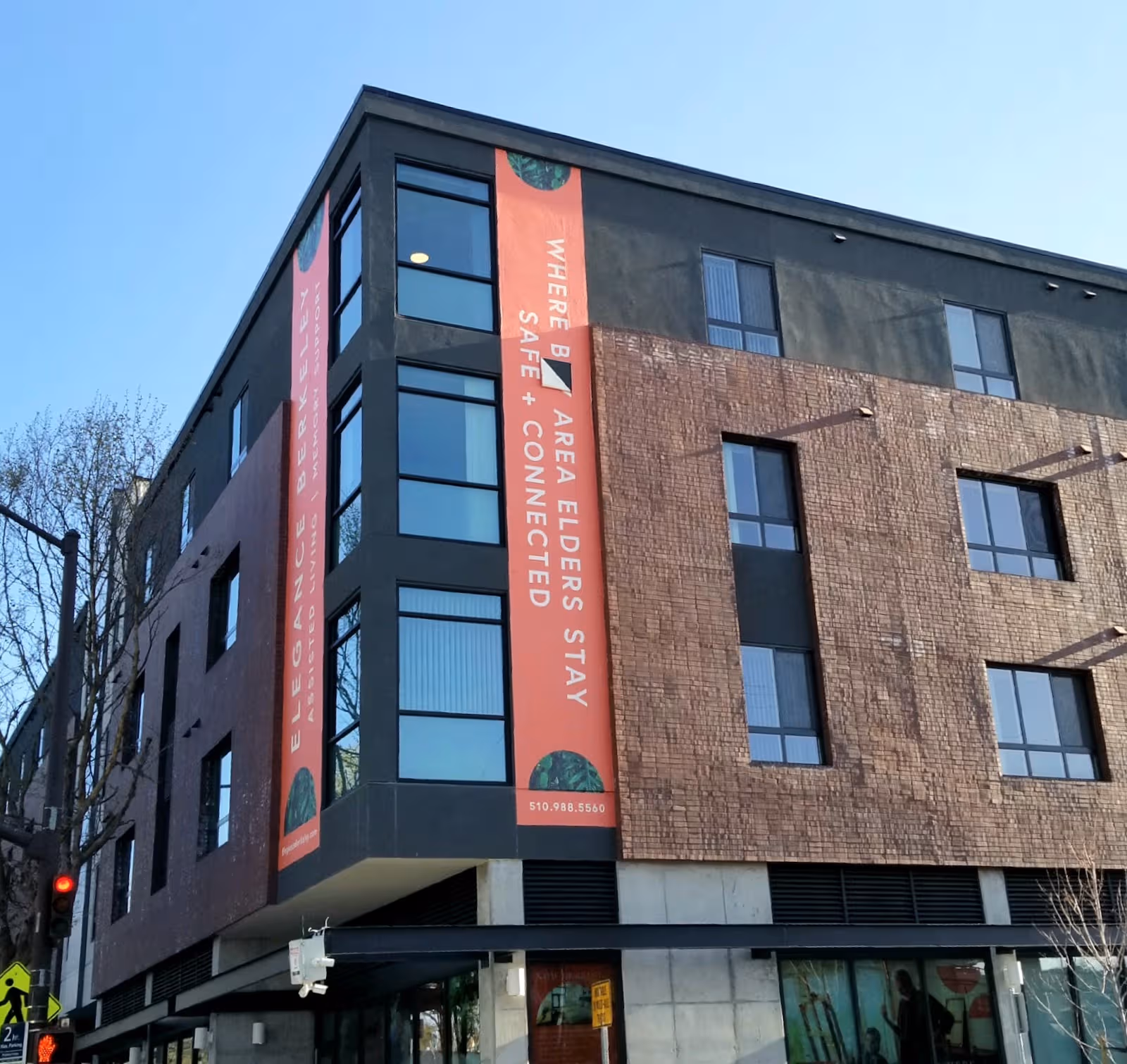 Exterior view of a modern multi-story brick building with vertical red banners advertising Elegance Berkeley.