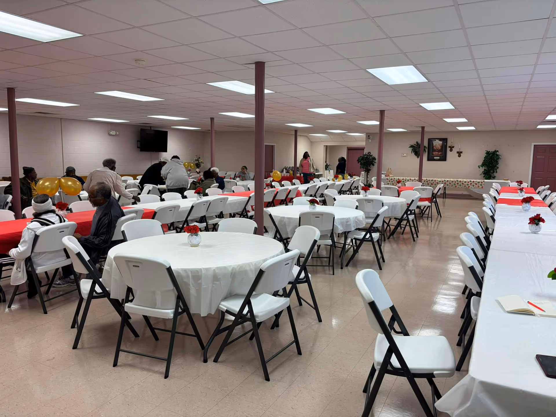 A spacious senior dining hall with round tables and white chairs.