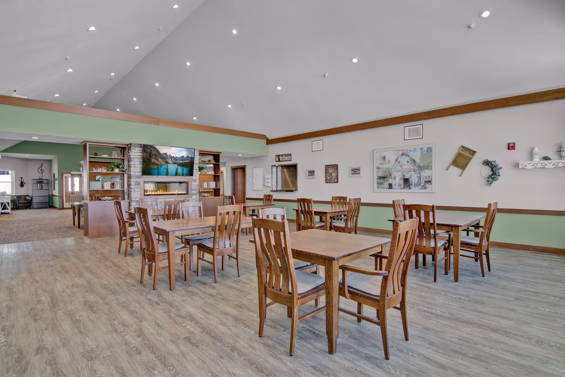 Interior of a senior living dining room with multiple wooden tables and chairs.