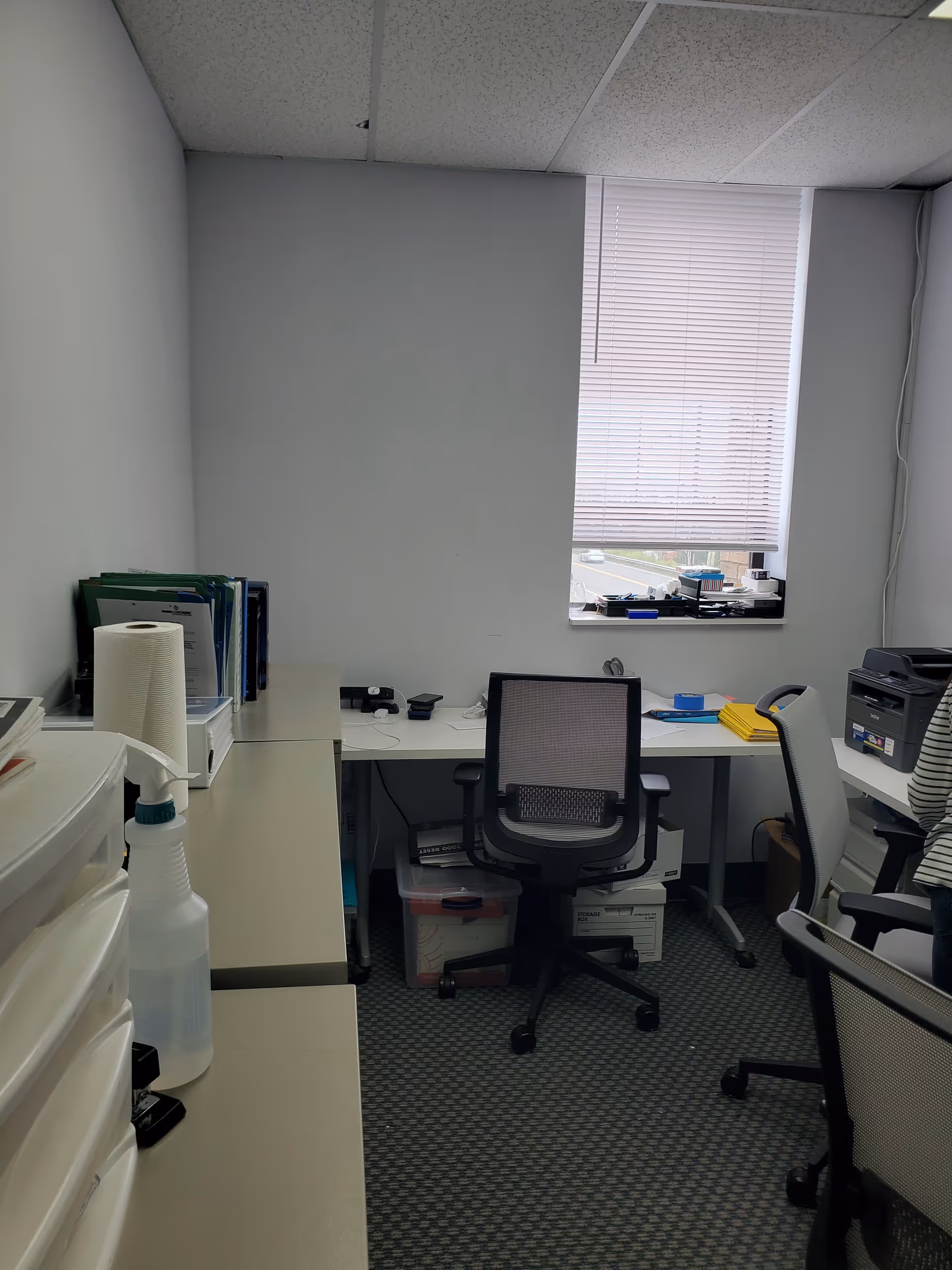 Facility office with desks, chairs, and window blinds.