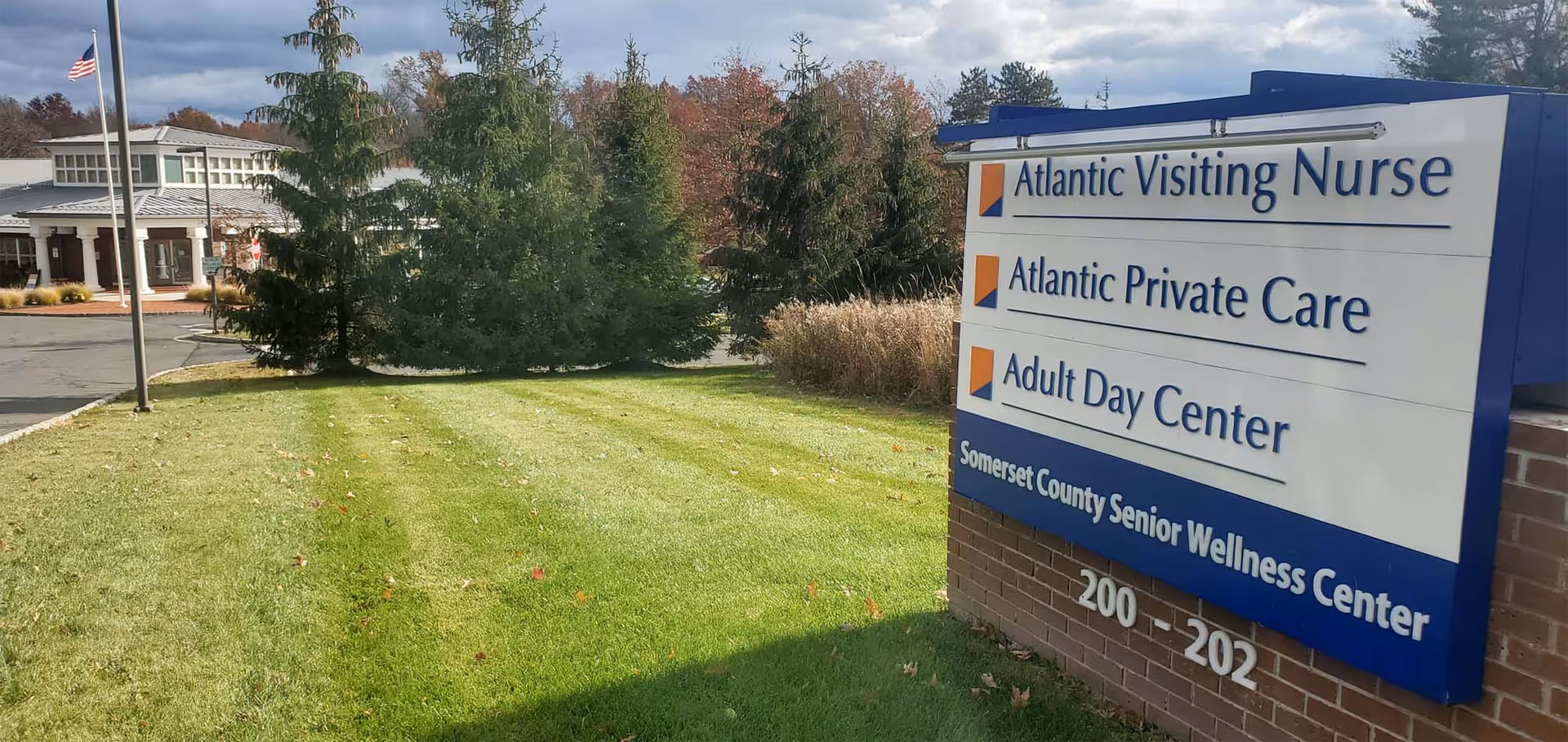Exterior view of a facility sign with Atlantic Adult Day Center beside a manicured lawn.