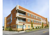 Brick three-story assisted living building with balconies along a street.